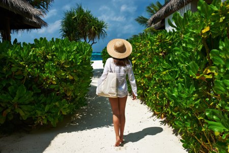Woman with bag and sun hat going to beach