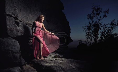 Glamour woman standing next to a rock