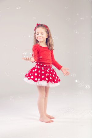 Funny lovely little girl playing with soap bubbles