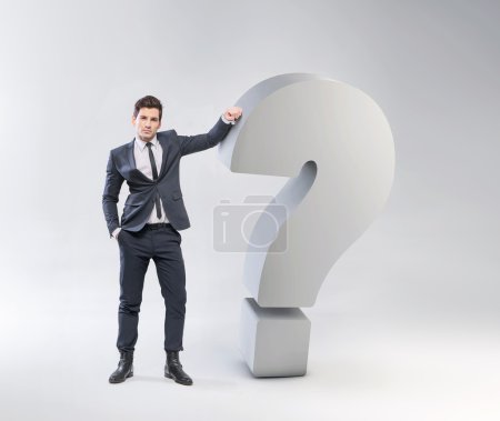 Elegant young man leaning against the question mark