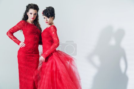 Two brunette girlfriends wearing red dresses