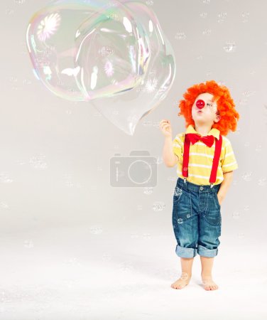 Funny picture of little clown making soap bubbles