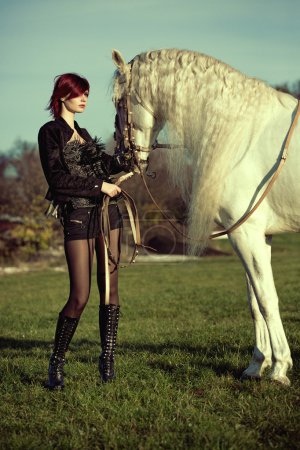 Attractive and shapely redhead with horse