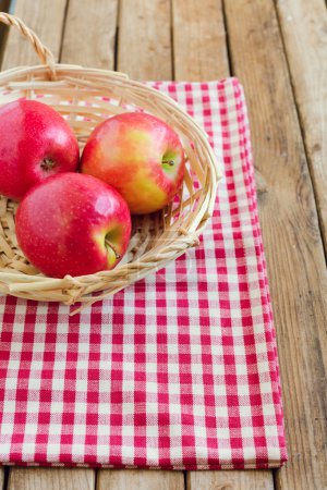 Red apples in basket on tablecloth