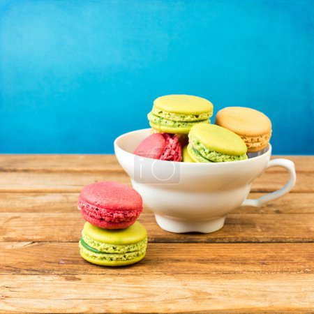 Macaroons in coffee cup on wooden table