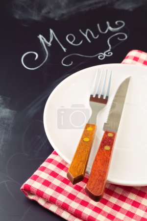 Plate, knife and fork on tablecloth