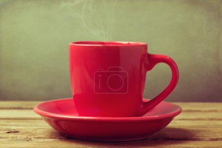 Close up of red coffee cup on wooden table over grunge background