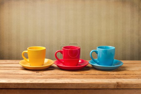 Three colorful coffee cups over vintage background