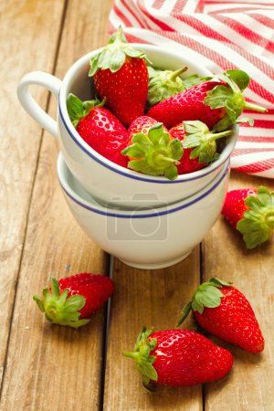Fresh strawberry in coffee cup on wooden tabletop