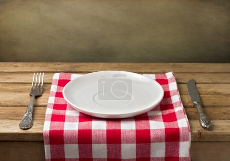 Empty plate on wooden table over grunge background