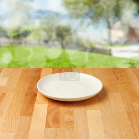 Empty plate on wooden table over nature background