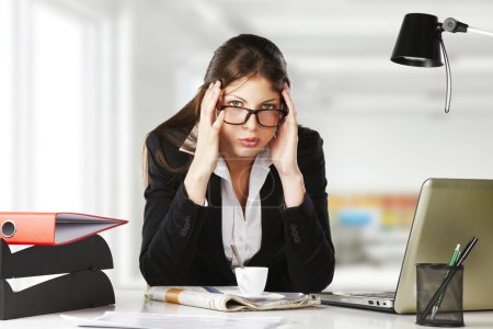 A young businesswoman is looking stressed as she works at her computer