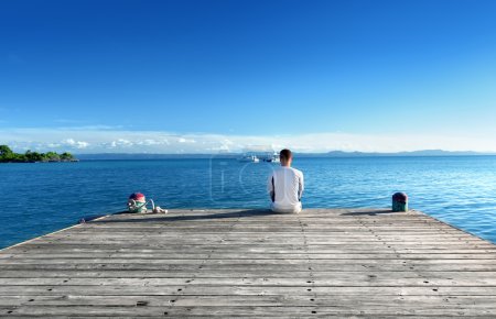 young man relax siting on pier