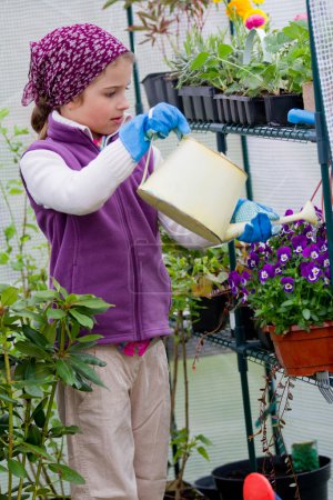 Gardening, planting concept - lovely girl watering flowers in the greenhouse