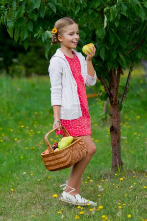 Fruits orchard, garden - lovely girl eating picked ripe pear