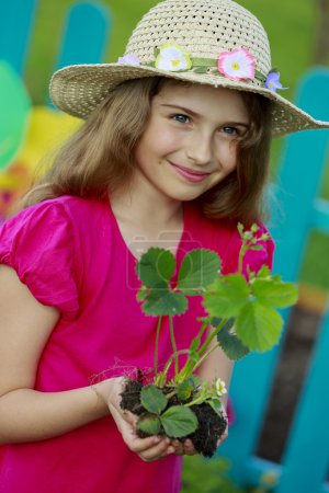 Gardening, planting - lovely girl with strawberry seedling