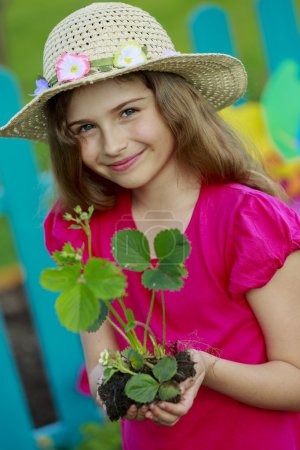 Gardening, planting - lovely girl with strawberry seedling