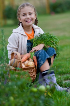 Vegetable garden, child - lovely girl with the basket of ecological harvests
