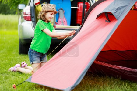 Camp in the tent - young girl setting a tent on the camping