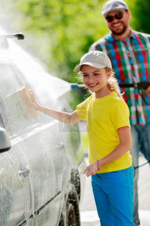 Carwash - young girl helping father to wash car