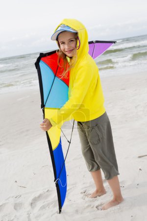 Fun on the beach - young girl playing with kite