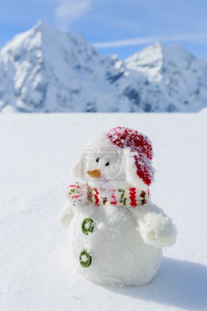 Winter, snow and sun - happy snowman and snowy mountains