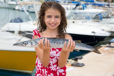 Happy kid fisherwoman with barracuda fish catch