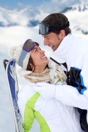 Couple standing on a snowy mountain in ski outfit