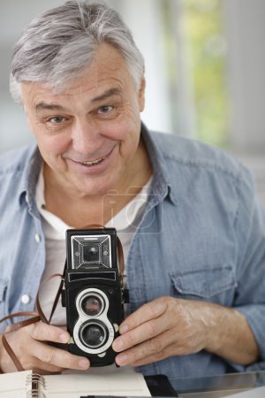Senior photographer holding vintage camera