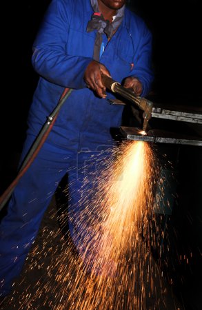Worker in Blue safety overalls working with Plasma cutter