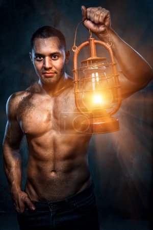 Muscular build man holding oil lamp