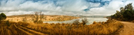 Panorama of beautiful winter landscape with lake and cloudy sky.