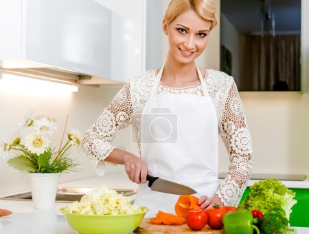 Smiling young woman preparing vegetarian salad