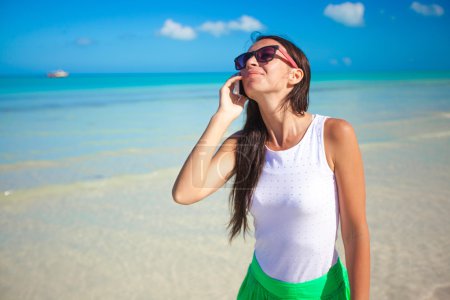Young beautiful woman talking on her phone on the beach