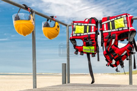 Safety helmets and life jackets hanging on railing