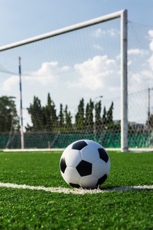 soccer ball on green grass in front of goal net