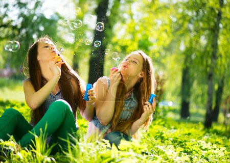 Teenage girls blowing soap bubbles