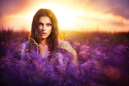 Beauty Girl Lying on a Meadow with Violet Flowers