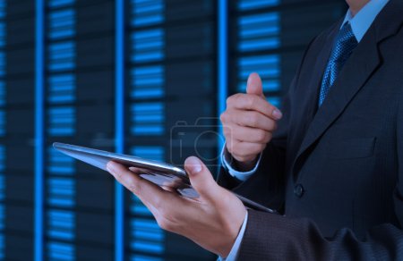 businessman hand using tablet computer and server room