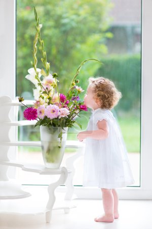 Baby girl smelling beautiful flowers