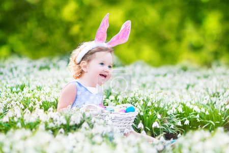 Girl wearing bunny ears playing with Easter eggs