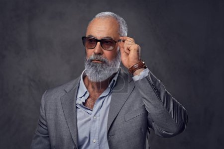 Stylish senior man with sunglasses against dark background