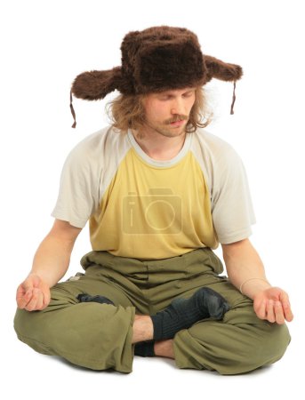 Meditating long-haired Russian man in cap with ear-flaps