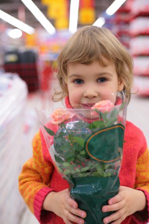 Child holds pot with flower in shop