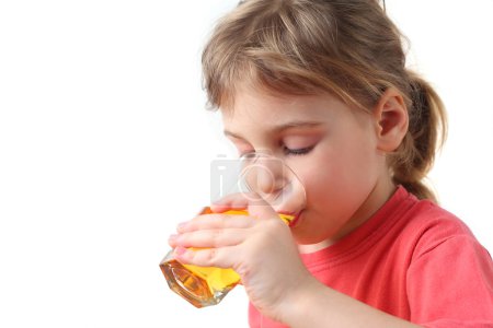 Little girl in red shirt holding glass with juice for one hand a