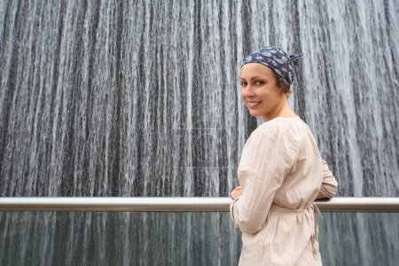 Young beauty woman in white shirt standing near big fountain and