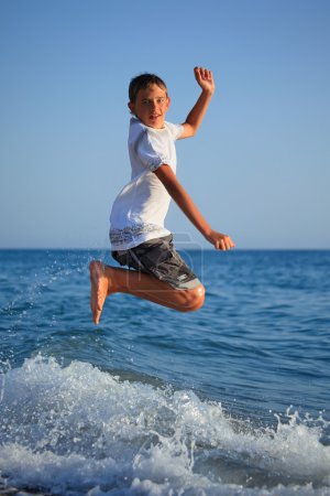 Jumping teenager boy on seacoast