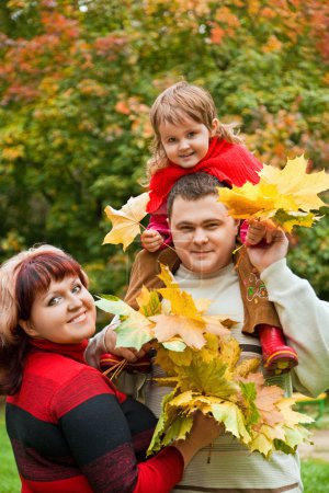 Married couple and little girl collect maple leafs In park in au