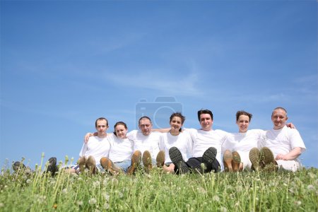 Friends in white T-shorts have a rest on a grass