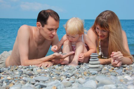 Parents with child on sea coast and pyramid of stones